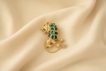 Gold tiger brooch with green gemstones on ivory fabric