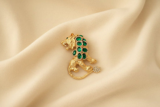 Gold tiger brooch with green gemstones on ivory fabric