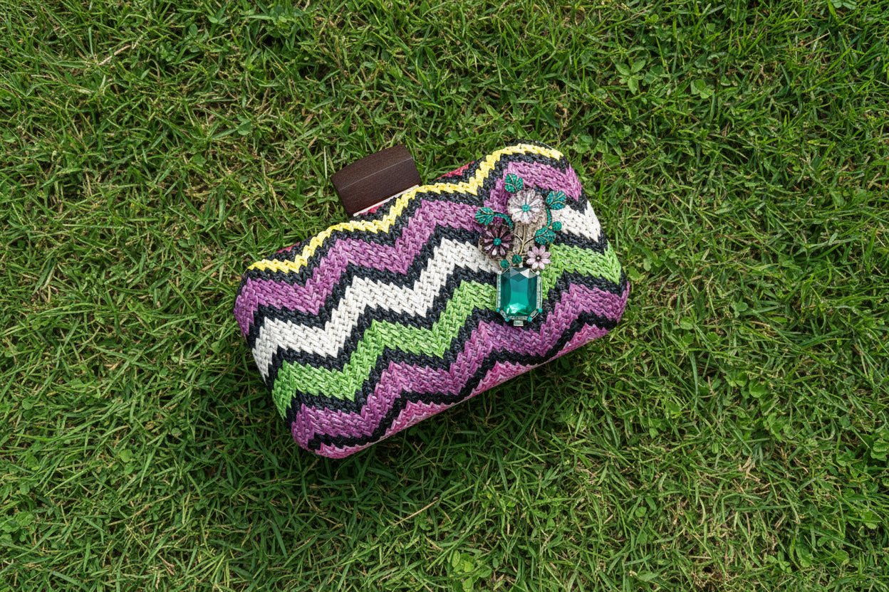 colorful chevron patterned clutch bag with a green floral brooch against a green grass background