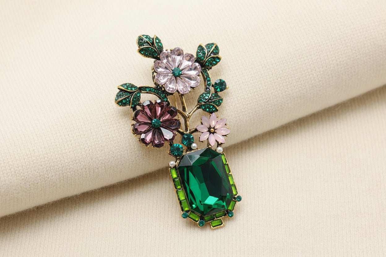 Decorative brooch with floral and gemstone design against an ivory sweater material background