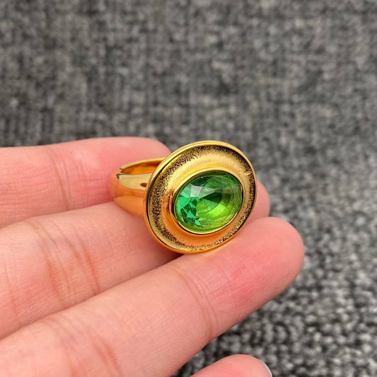 fingers holding a gold ring with oval emerald cubic zirconia stone