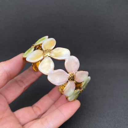 Floral cuff bracelet held in a hand against a dark background