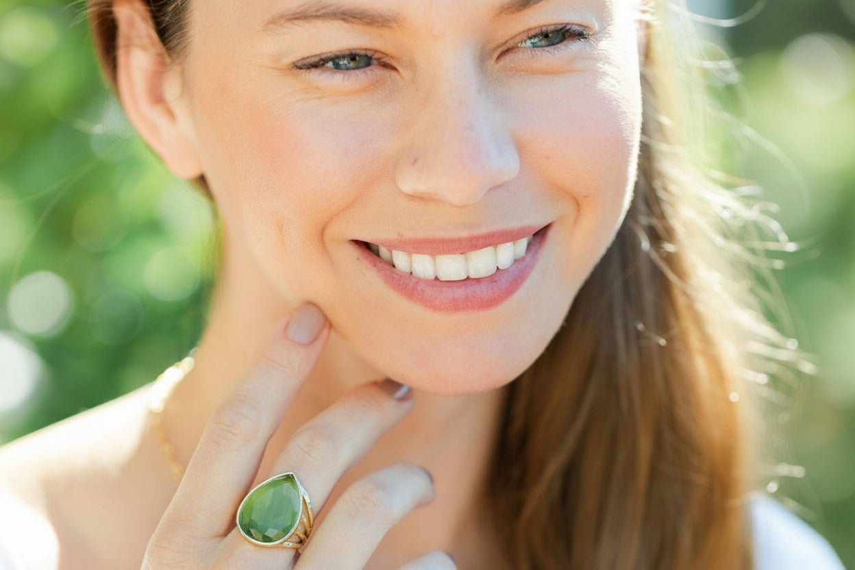 Woman wearing a green teardrop ring with a blurred green background
