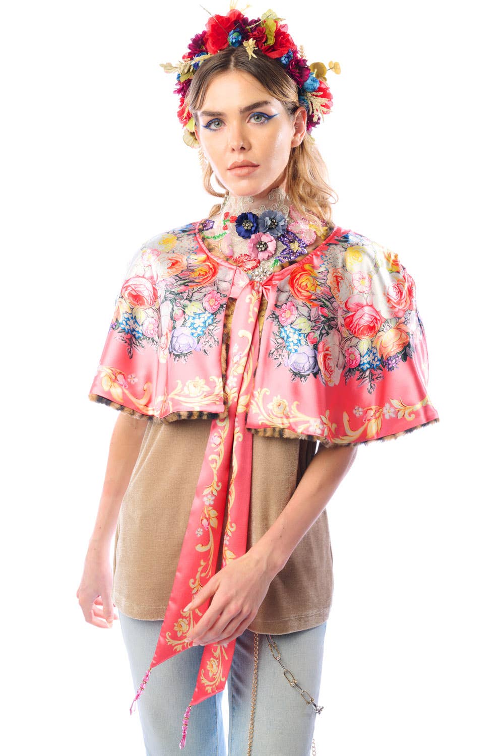 Woman wearing a colorful floral cape with a white background. Floral satin side of reversible faux fur cape showing botanical print lining