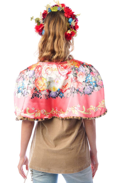 Back view of woman wearing a reversible floral cape with a white background