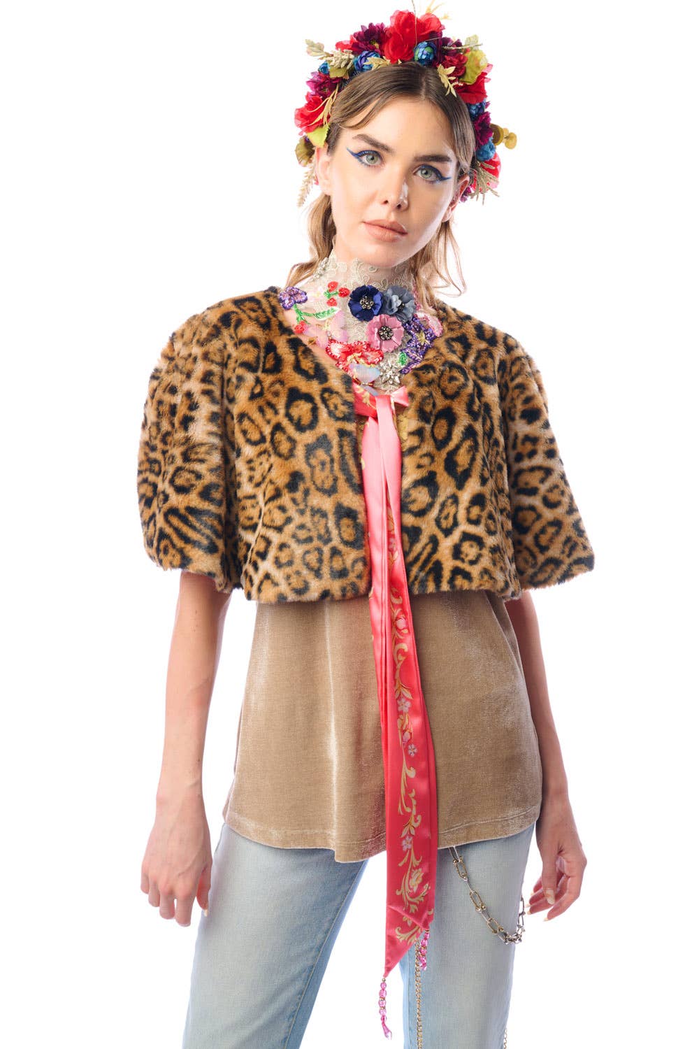 Woman wearing a leopard faux fur cape, floral headband, and colorful scarf on a white background