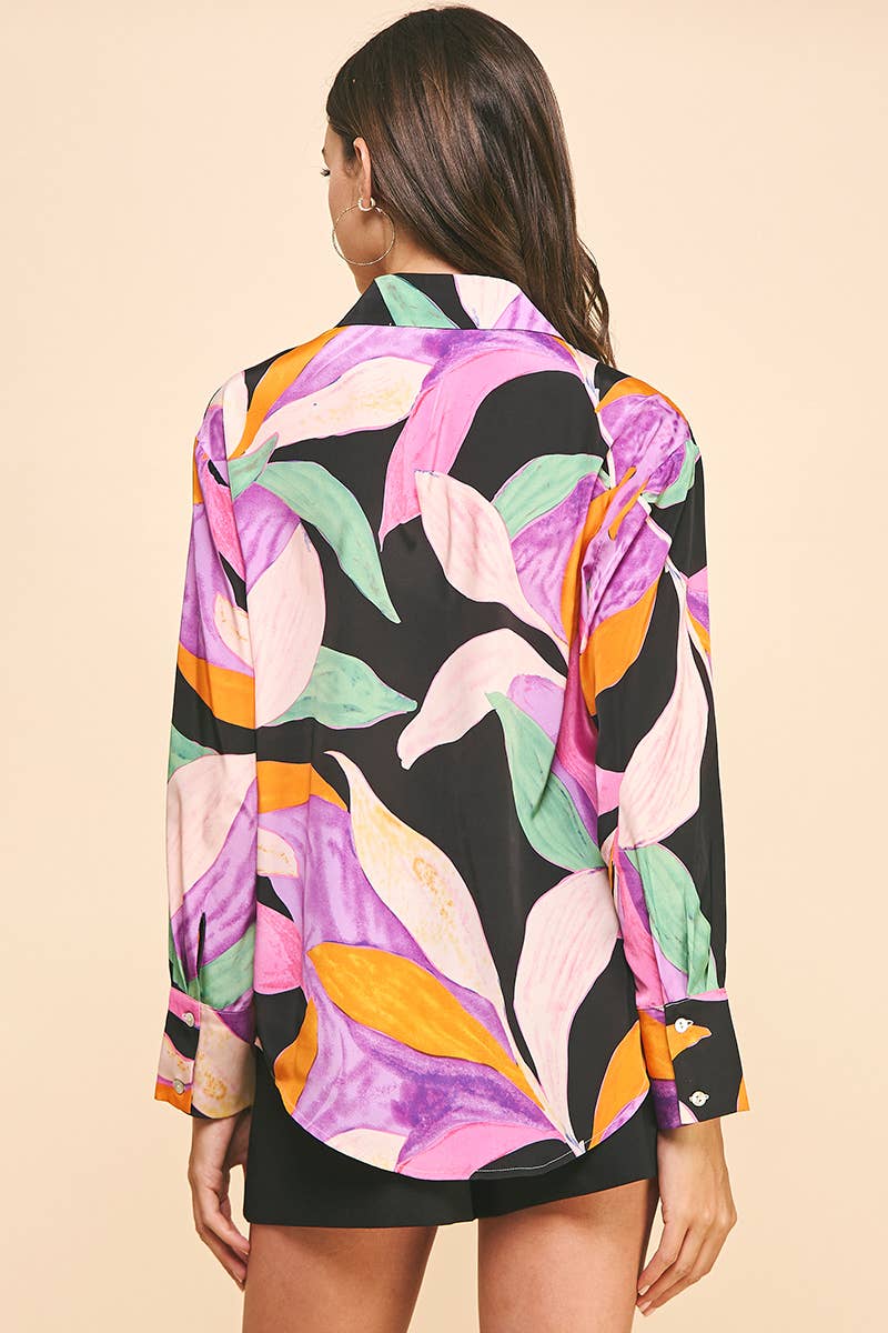 Back view of woman wearing pink and purple floral button down blouse with black shorts