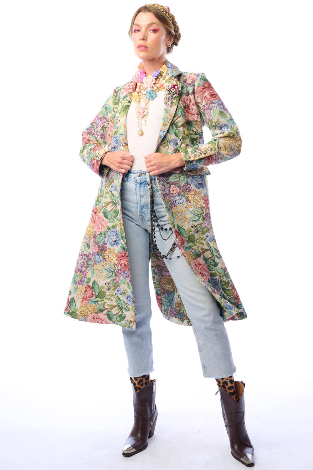 Woman wearing a colorful floral coat and light denim jeans on a white background