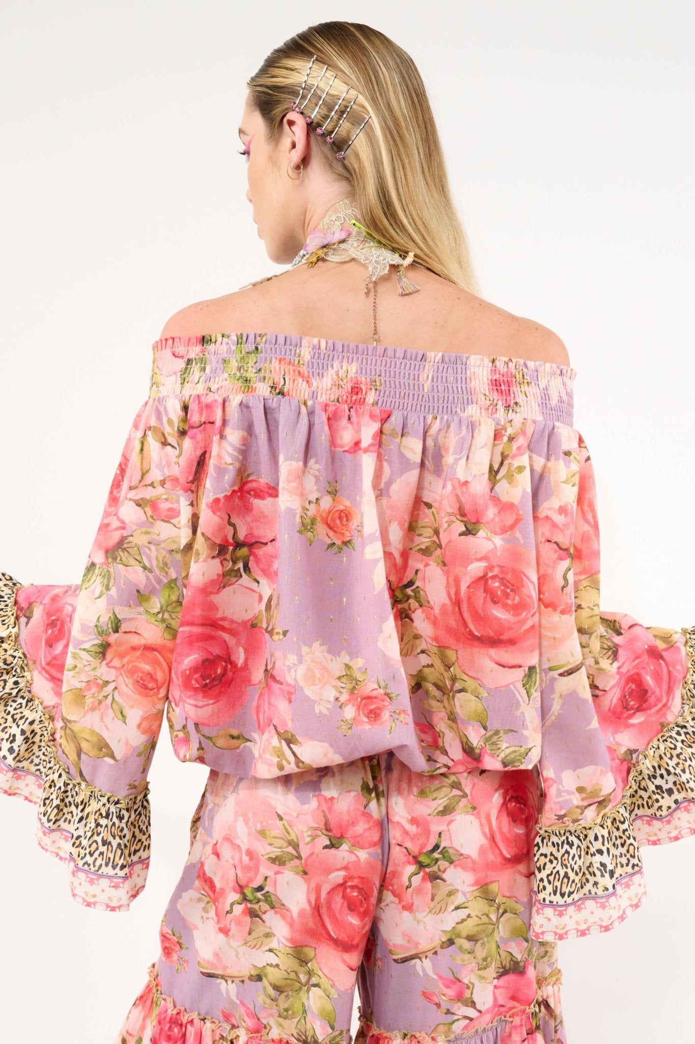 Woman wearing a floral off-shoulder top with ruffled sleeves on a white background