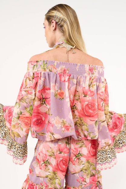 Woman wearing a floral off-shoulder top with ruffled sleeves on a white background