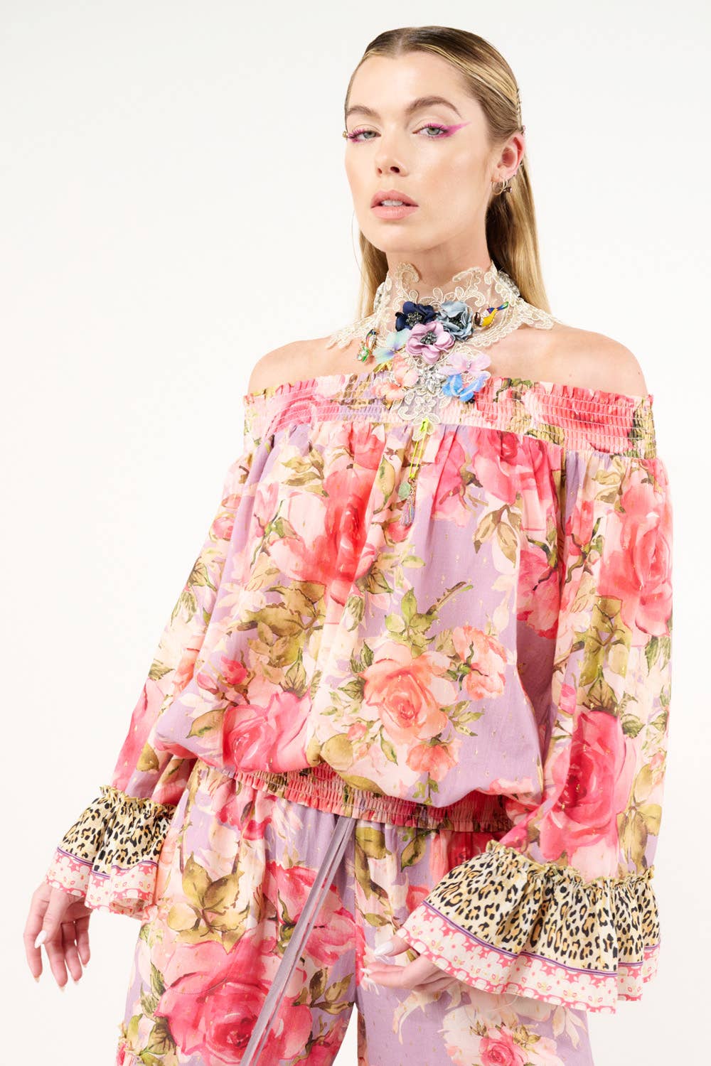 Woman wearing a floral off-shoulder top with leopard print details on a white background