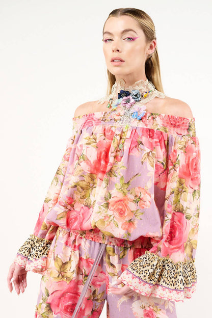 Woman wearing a floral off-shoulder top with leopard print details on a white background