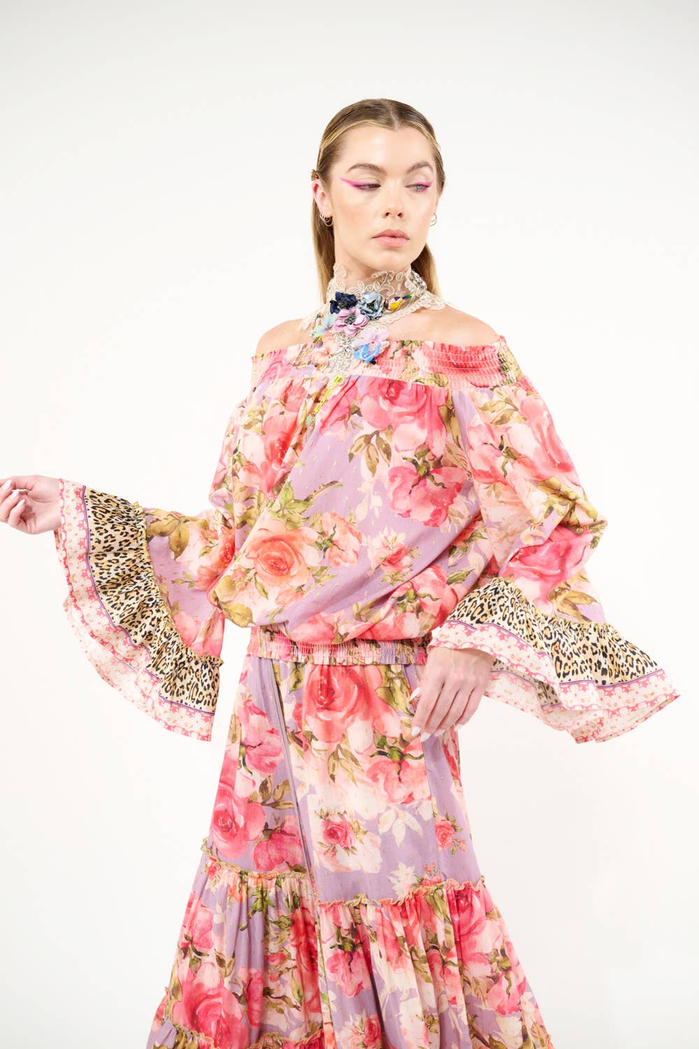 Woman wearing a floral top and pants with leopard print sleeves on a white background