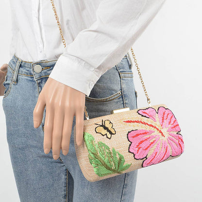 mannequin wearing a white shirt and jeans with raffia purse with butterfly and floral embroidery and gold chain shoulder strap