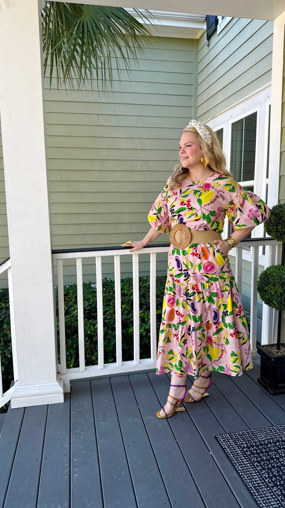 Woman in a fruit and floral printed skirt and matching top standing on a porch