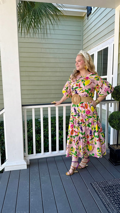 Woman in a fruit and floral printed skirt and matching top standing on a porch