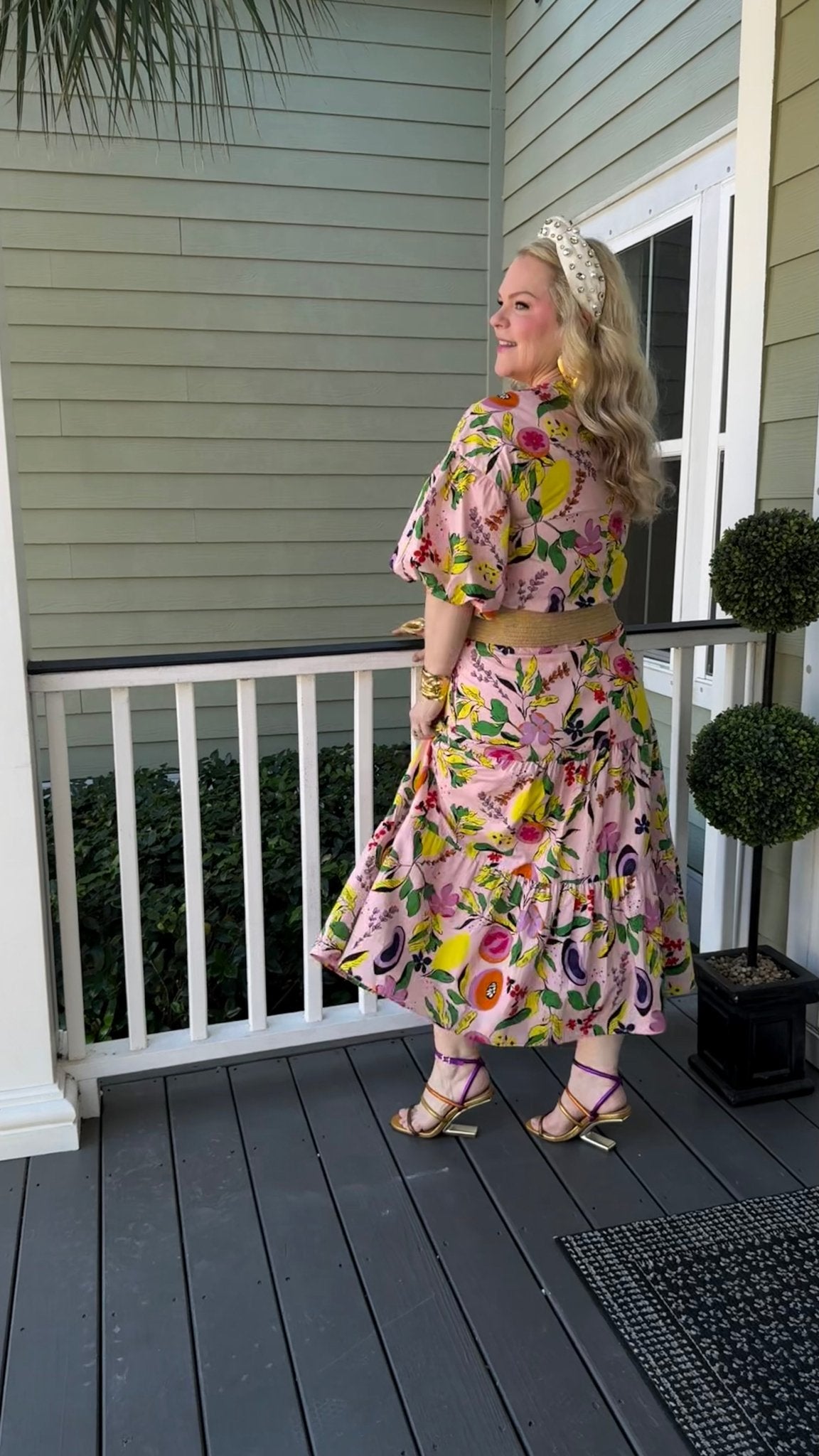 Woman in a fruit and floral printed skirt and top standing on a porch