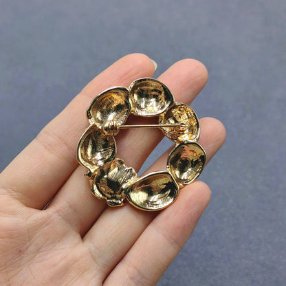 back view of strawberry brooch held in a hand against a gray background