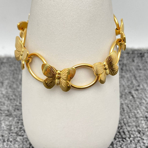 Gold butterfly link bracelet displayed on white stand