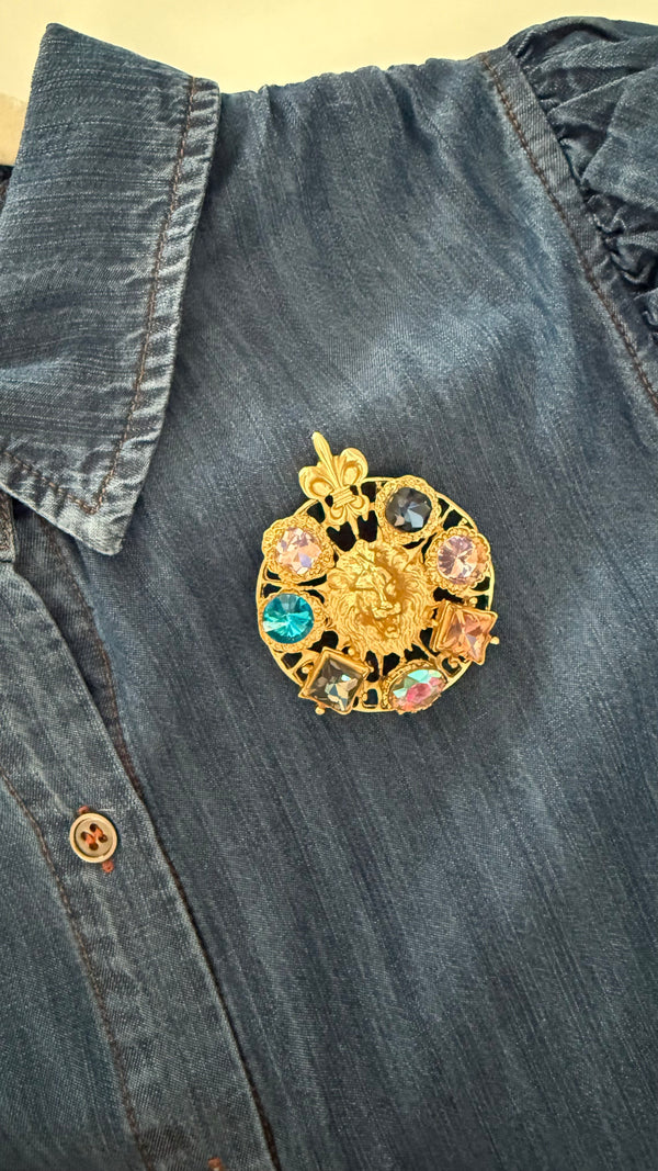 Gold filigree lion brooch with multicolor crystals pinned on denim — statement jewelry from JuJu Loves