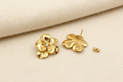 Gold flower-shaped earrings on a light ivory background