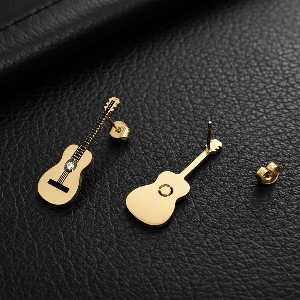 Gold guitar-shaped earrings on a textured black leather surface. One earring is showing the back post detail.