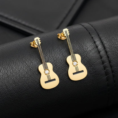Gold Guitar-shaped earrings on a black leather material background