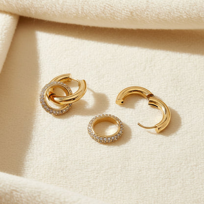 Gold hoop earrings with clear embedded stones on an ivory background