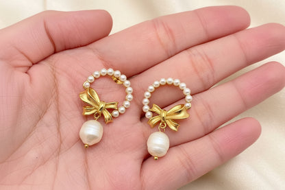 Gold bow and pearl wreath earrings with pearl drops held in a hand