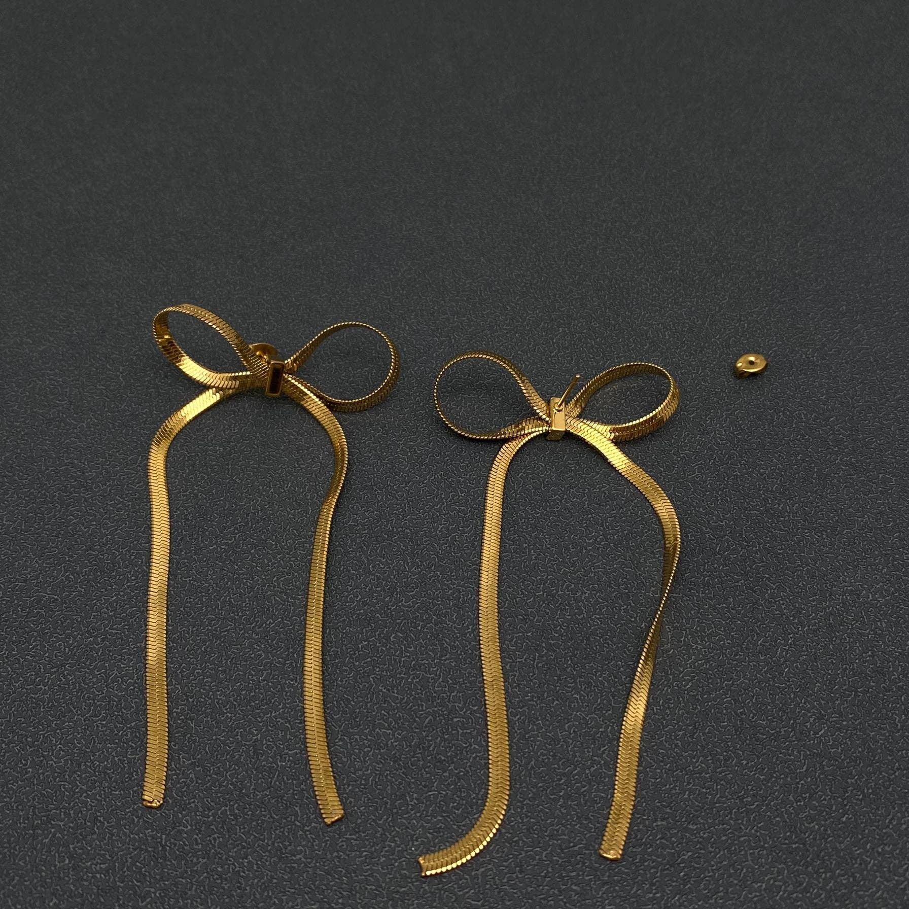 gold chain bow earrings on a black background