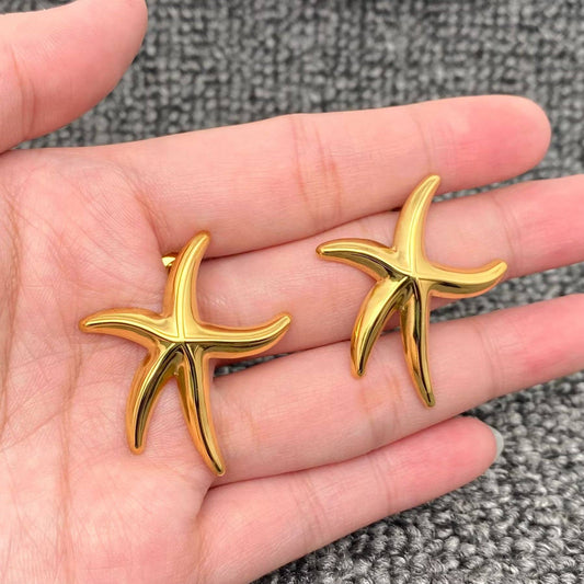a pair on gold starfish stud earrings in the palm of the hand