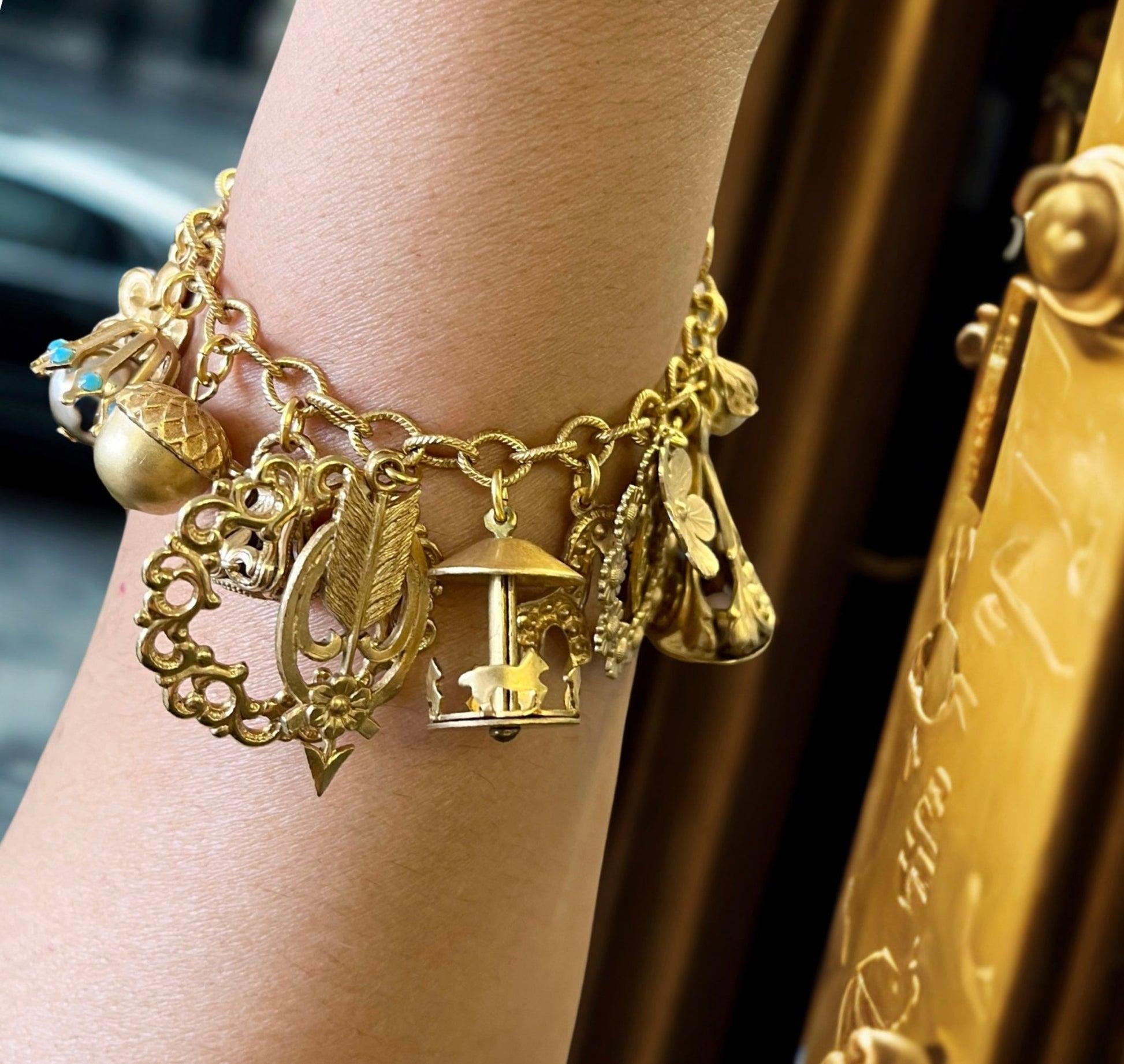 Vintage gold charm bracelet with curated filigree charsm including carousel and daisy charms 14K gold plated brass in an outdoor setting from JuJu Loves Charleston SC