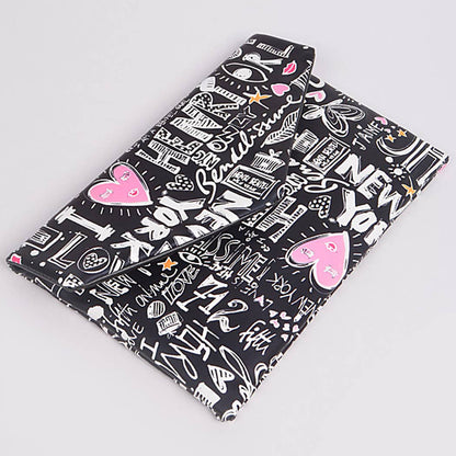 Graffiti print envelope clutch — front flat lay view showing colorful doodle print on black background