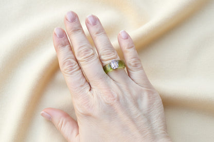 Hand wearing a green acrylic ring with an ivory fabric background