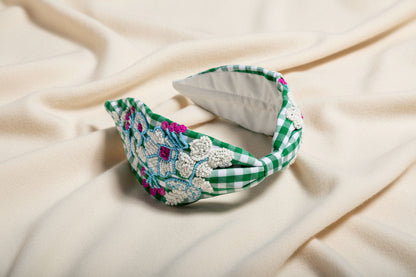 Green and white gingham knotted headband with hand-beaded floral embellishments on an ivory fabric background