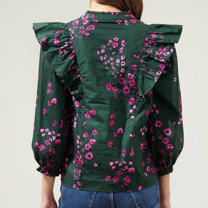 Back view of dark floral ruffle top in front of a white background