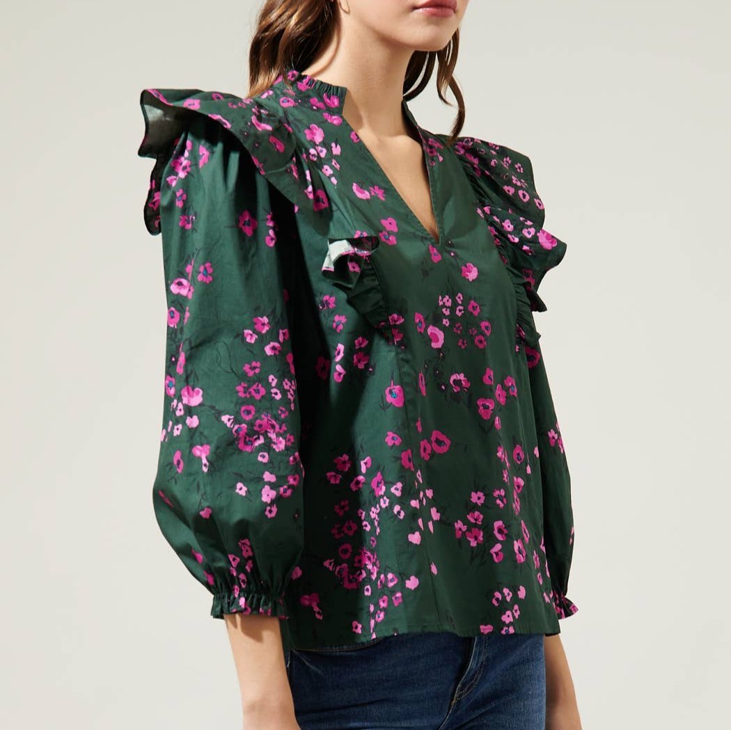 Side view of dark floral ruffle top and jeans against a white background