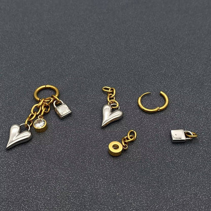 gold and silver heart, lock, and crystal charm earrings on a dark grey background