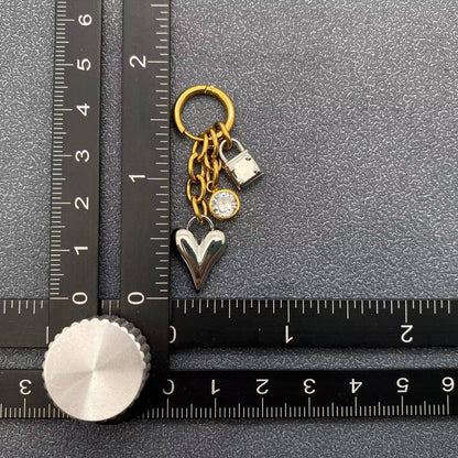 Earring with heart and lock charms next to a ruler on a textured surface