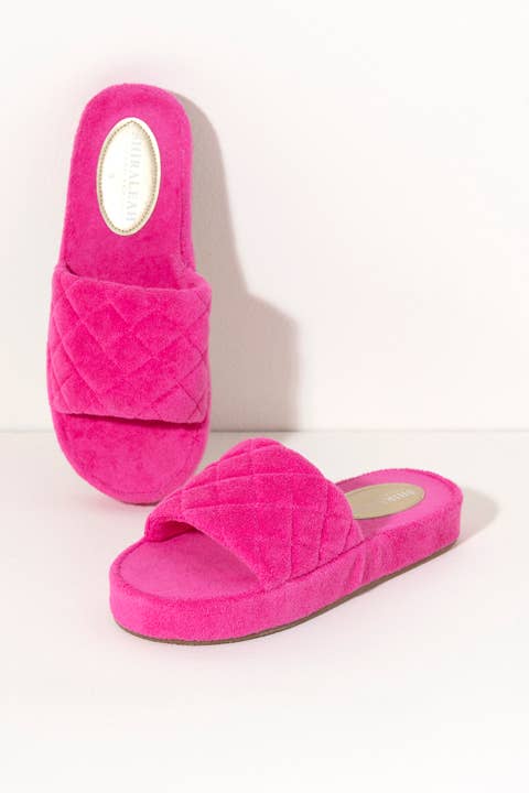 Hot pink terrycloth pool slides with quilted terry fabric and EVA sole against a white background