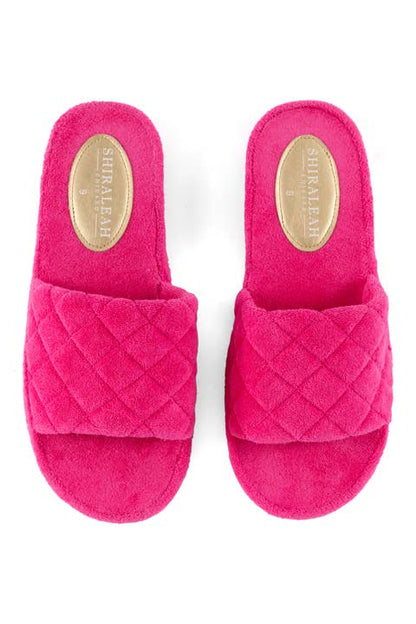 A pair of pink terrycloth pool slides with a diamond pattern on the straps and a flat rubber-like sole against a white background