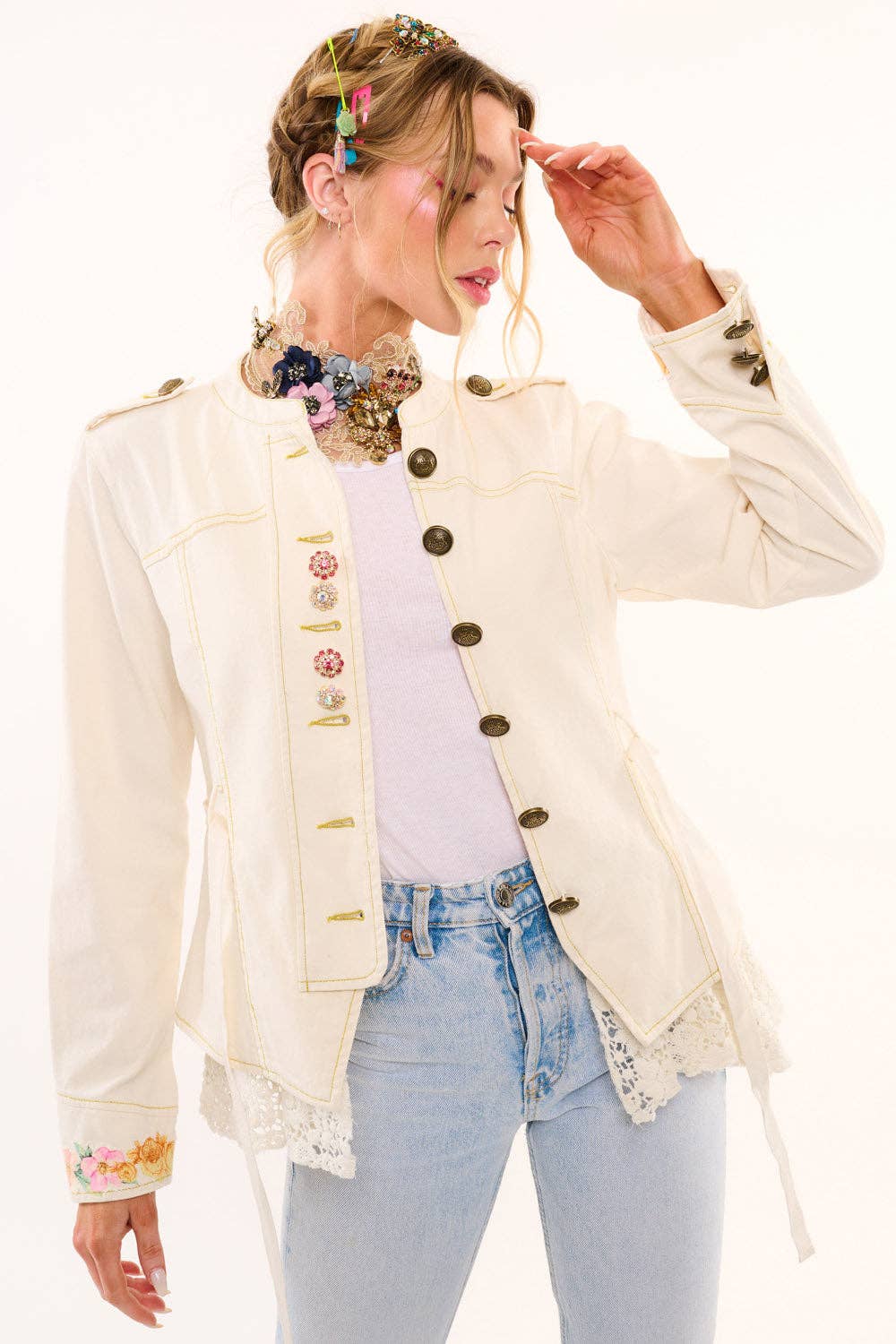 Woman wearing a decorative beige jacket with floral embellishments on a white background