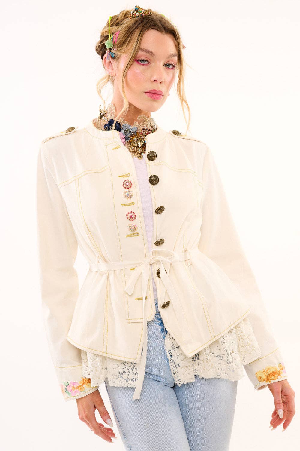 Woman wearing a cream-colored jacket with floral details on a white background