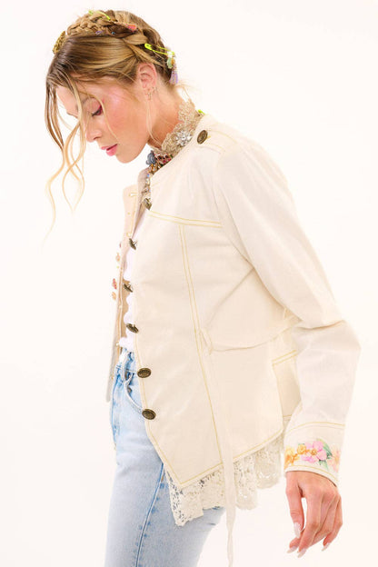 Woman wearing a cream-colored jacket with floral embroidery on a white background