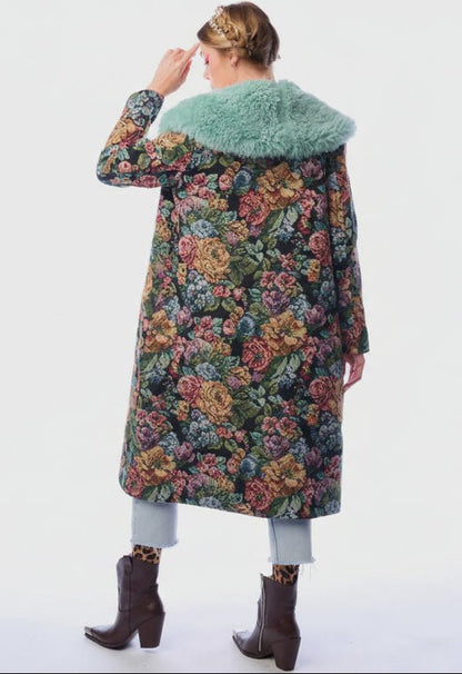 Back  view of a woman wearing a floral coat with a fur-lined collar on a white background