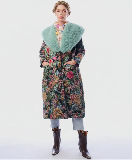 Woman wearing a long floral coat with a fur collar on a white background