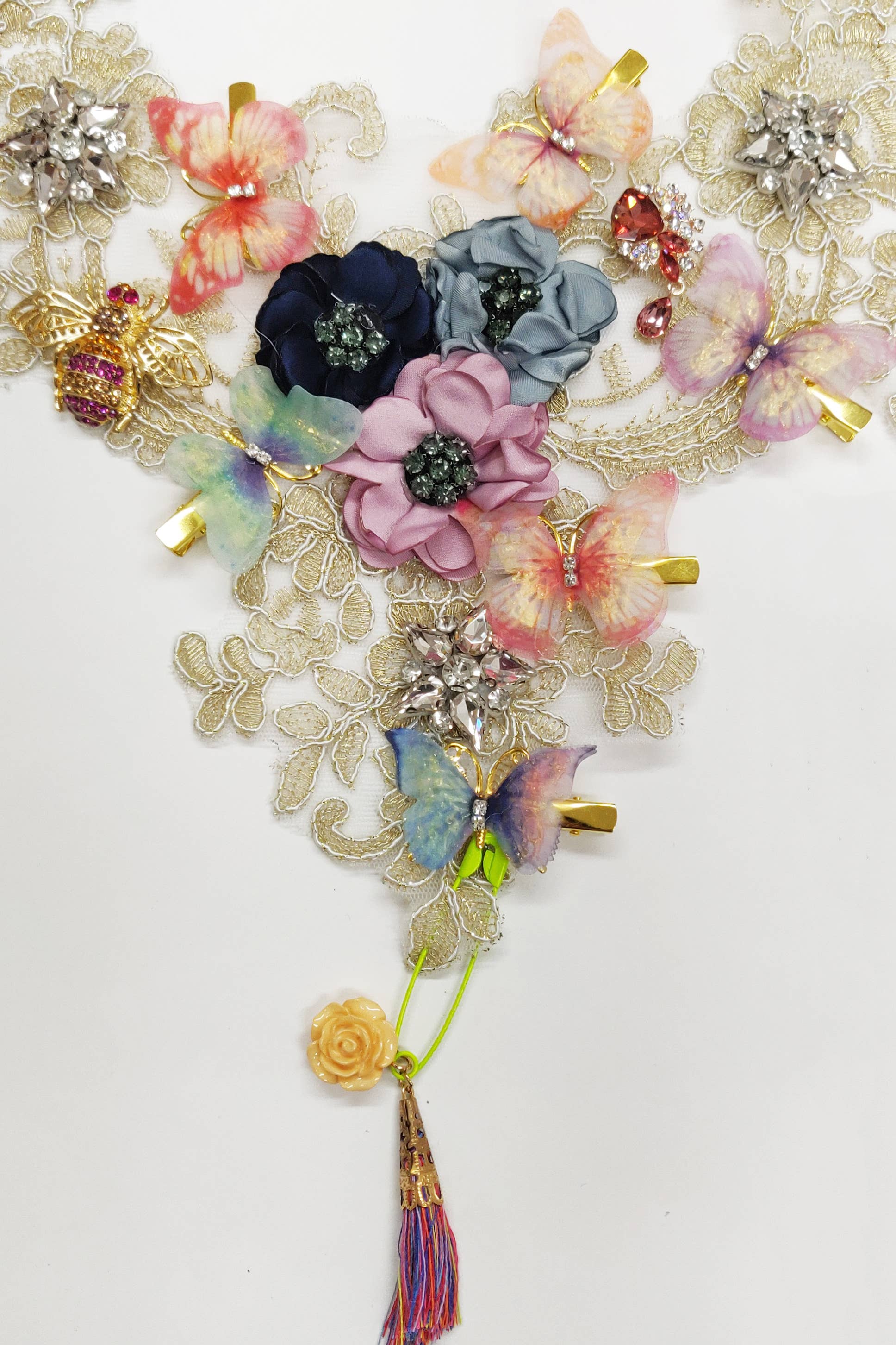 Close-up of handmade lace bib necklace showing crystal brooches and fabric flowers