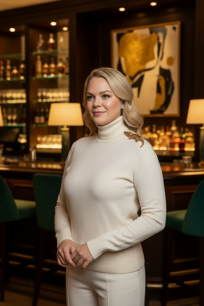 Woman in a white outfit standing in a bar setting with shelves of bottles in the background. She has a large crystal crocodile brooch on her shoulder.