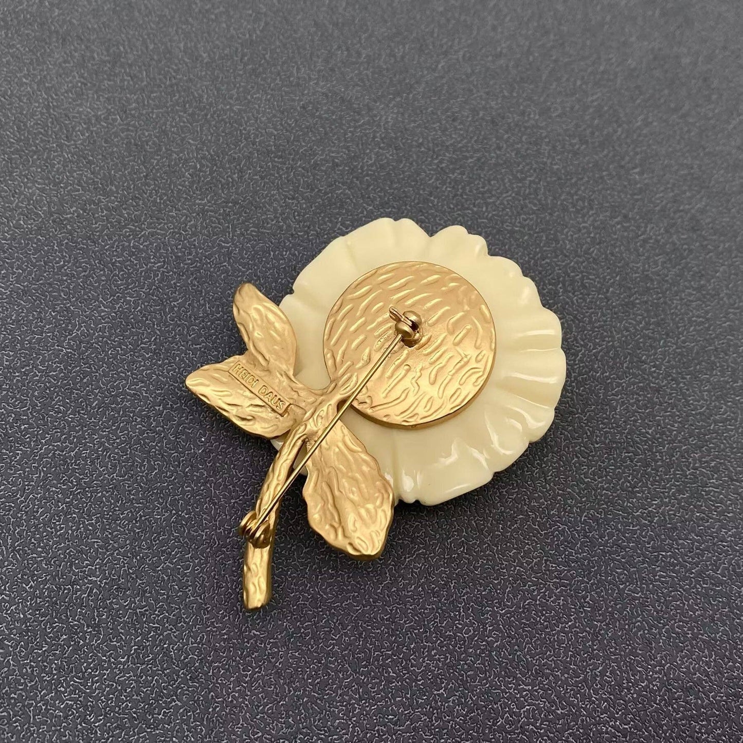 Gold and white brooch on a dark gray background