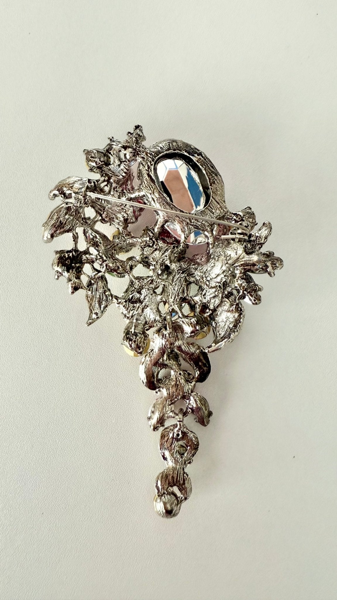 Back view of decorative brooch showing pin closure on a light gray background